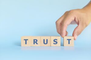 a person placing a block with the word trust on it