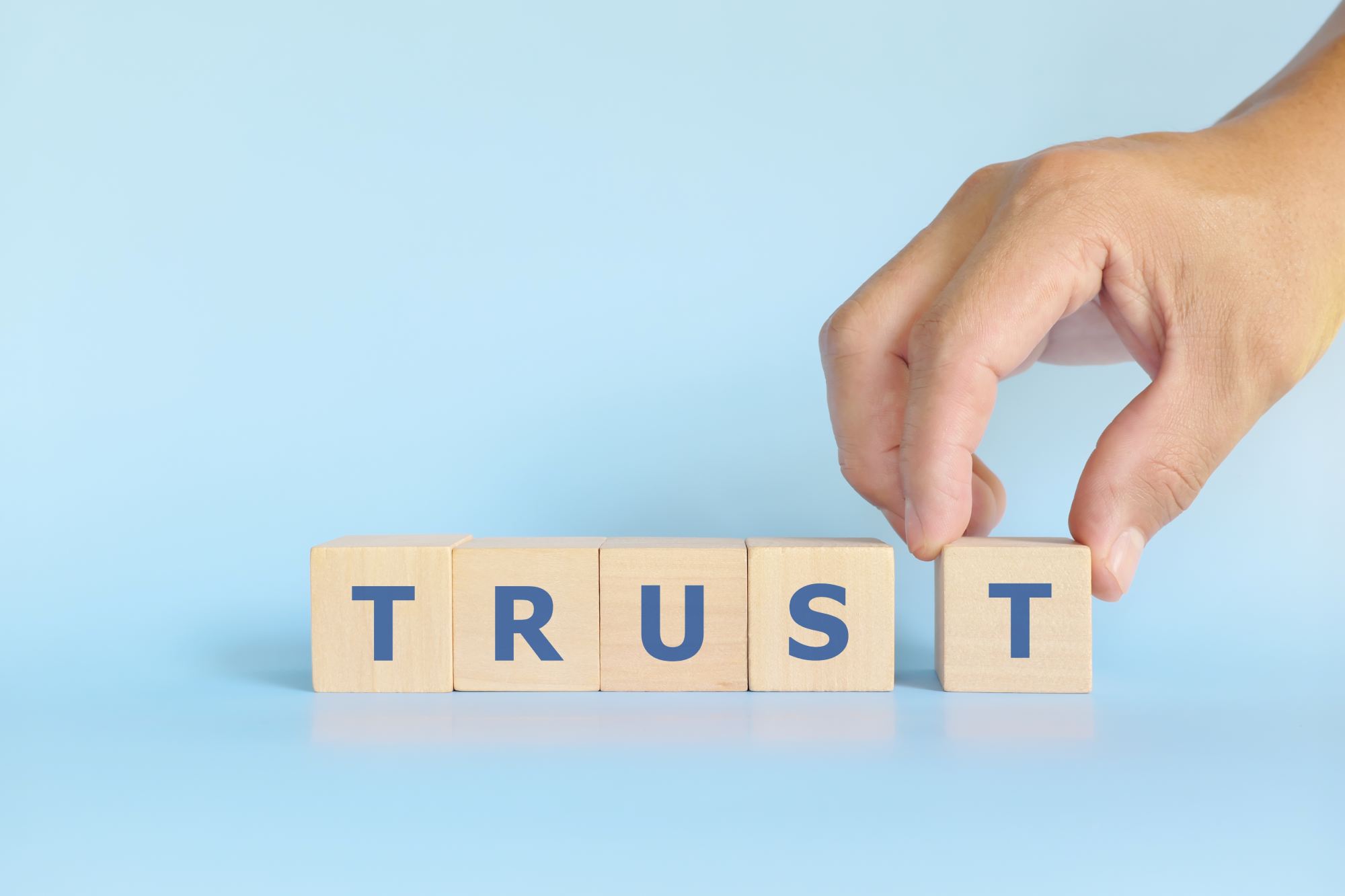 a person placing a block with the word trust on it