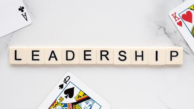 scrabble tiles spelling out the word leadership and playing cards
